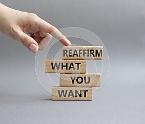 Goals symbol. Wooden blocks with words Reaffirm what you want. Beautiful grey background. Businessman hand. Business and '