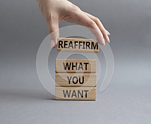 Goals symbol. Wooden blocks with words Reaffirm what you want. Beautiful grey background. Businessman hand. Business and Reaffirm