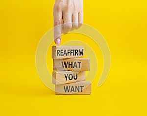 Goals symbol. Wooden blocks with words Reaffirm what you want. Beautiful yellow background. Businessman hand. Business and