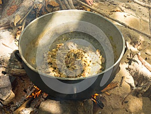 Goat being simmered in a cast iron pot on a beach in the caribbean