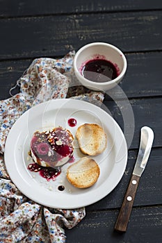 Goat cheese with berry sauce, balsamic vinegar and nuts on a white plate