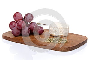 Goat cheese, grapes and provencal herbs on a wooden cutting boar