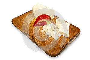 Goat cheese with tomato and chopped onion on a wooden chopping board isolated