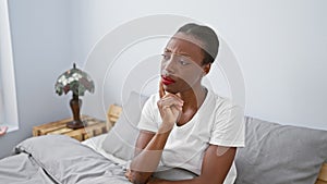 Gobsmacked african american woman lying in bed, awestruck expression painting her beautiful face - hands-on chin in disbelief,