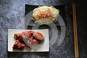 Gochujang ribs and noodles on dark cement background