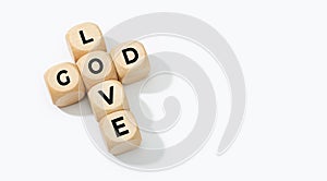 God is Love concept. Wooden blocks forming a cross with text isolated on white background