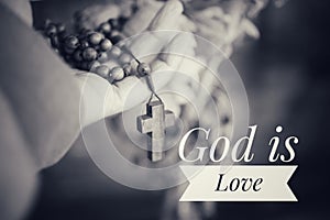 God is Love. Hand holding Rosary in black and white background. Senior woman holding rosary with open hand with Jesus Christ Cross