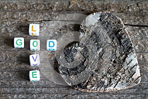 God is love letters with cross and heart religion concept on wooden background