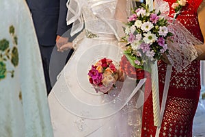 The godmother holding the wedding candle and her bouquet 