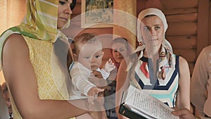 Godmother holds a little boy in arms during baptism ritual