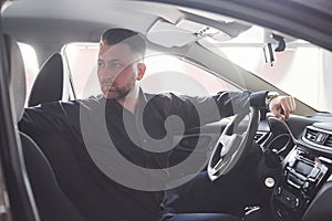 Going back. Side view of man sitting in the modern car with black interior