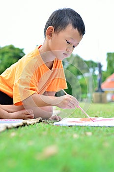 Going back to school : Boy drawing and painting over green grass