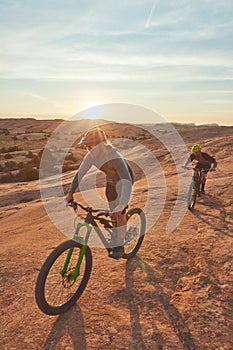 Going the distance. Full length shot of two young male athletes mountain biking in the wilderness.