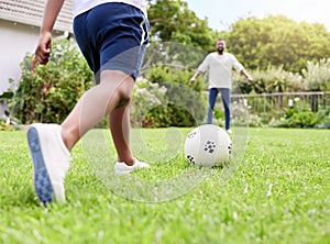 Going for a goal. Closeup shot of a little boy kicking a soccer ball to his father while playing together outdoors.