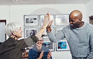 Going in for a high five. two cheerful businesspeople giving each other a high five inside of the office during the day.