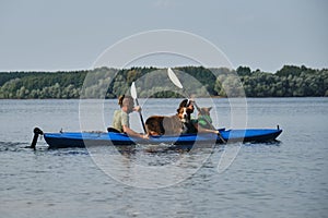 Going kayak boating with dogs on river, active pets concept, happy dog and owner on adventure. Young couple with dreadlocks having