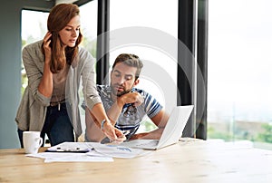 Going over the budget. a young couple working on their household budget and paying bills online.