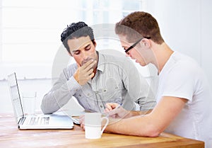 Going over design points. Shot of two young business professionals in deep conversation over a laptop.