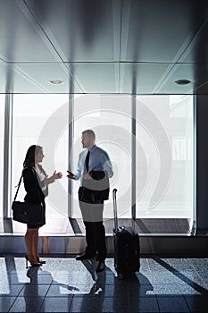 Going places with business. two businesspeople talking together in an airport.