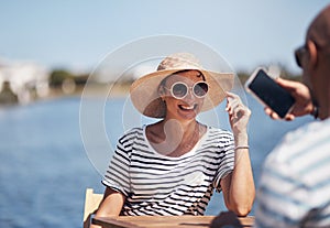 This is going to be a nice photo. a cheerful young woman getting her picture taken by her boyfriend outside while they