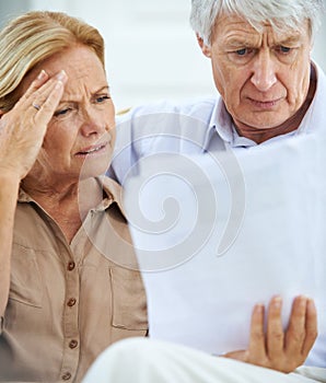 This is going to be a tough month. an elderly couple looking frustrated while going over their paperwork together.