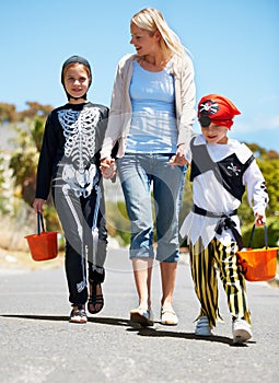 Going trick or treating. Children in costume going treat or treating with their mom.