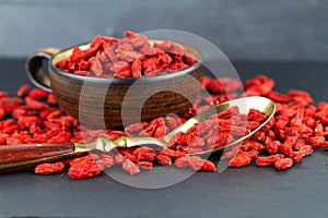 Goji berries in a cup and vintage spoon on gray slate background