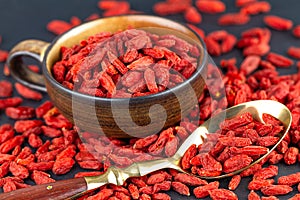 Goji berries in cup with vintage spoon on gray slate. View from above, selective focus