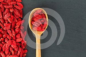 Goji berries. Spoon with organic berry over gray slate background