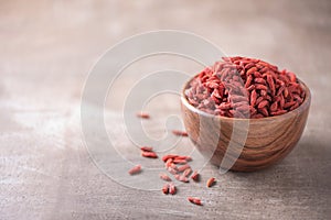 Goji berries in wooden bowl on wood textured background. Copy space. Superfood, vegan, vegetarian food concept. Macro of goji