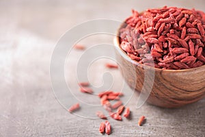 Goji berries in wooden bowl on wood textured background. Copy space. Superfood, vegan, vegetarian food concept. Macro of goji