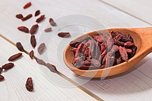 Goji berries in a wooden spoon on a white background.