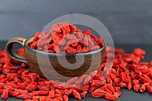 Goji berry cup many dried goji berries on grey slate. Selective focus