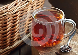 Goji berry tea in a glass cup on rustic wood with wicker nearby, closeup, naturopathy photo