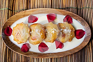 Gokul Pithe a sweet fried dumpling a dessert from India decorated on a textured prop and garnished with rose petals