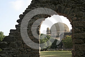 Gol Gumbaz framed with an opening in a stone wall in Bijapur, Karnataka, India