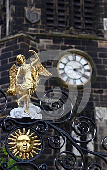 Gold Angel On a Church Gate with the Church Clock in the Background