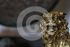 Gold Asian Lion Statue With Gong in Background Shallow DOF