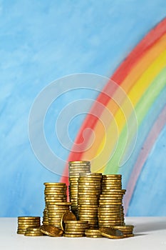 Gold Australian dollar coins against a blue sky and rainbow back