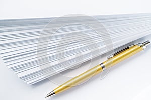 Gold ball point pen lying on the pile of paper for those who write