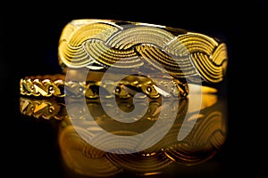 Gold bangle on black reflective surface, Traditional indian gold bangles