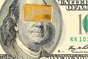 Gold bar on 100 dollar bill banknote closeup