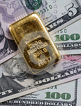 Gold bar against the background of dollar bills