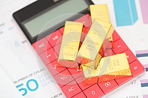 Gold bar on calculator calculator on paper document