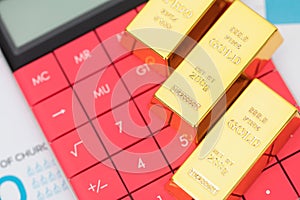 Gold bar on calculator calculator on paper document