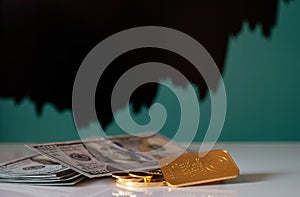 Gold bar, coins and a hundred-dollar bills on the background of the growth chart.