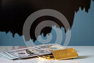 Gold bar, coins and a hundred-dollar bills on the background of the growth chart. photo