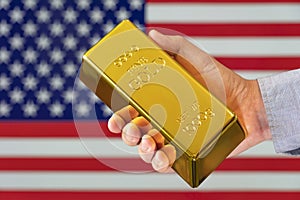 gold bar in a man& x27;s hand on the background of the American flag. America& x27;s gold. Trading on the stock exchange