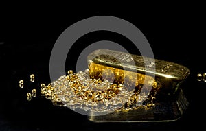 Gold bar on a pile of gold granules.