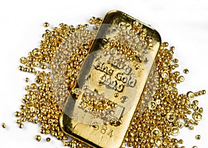 Gold bar in a pile of gold granules. Isolated on a white background